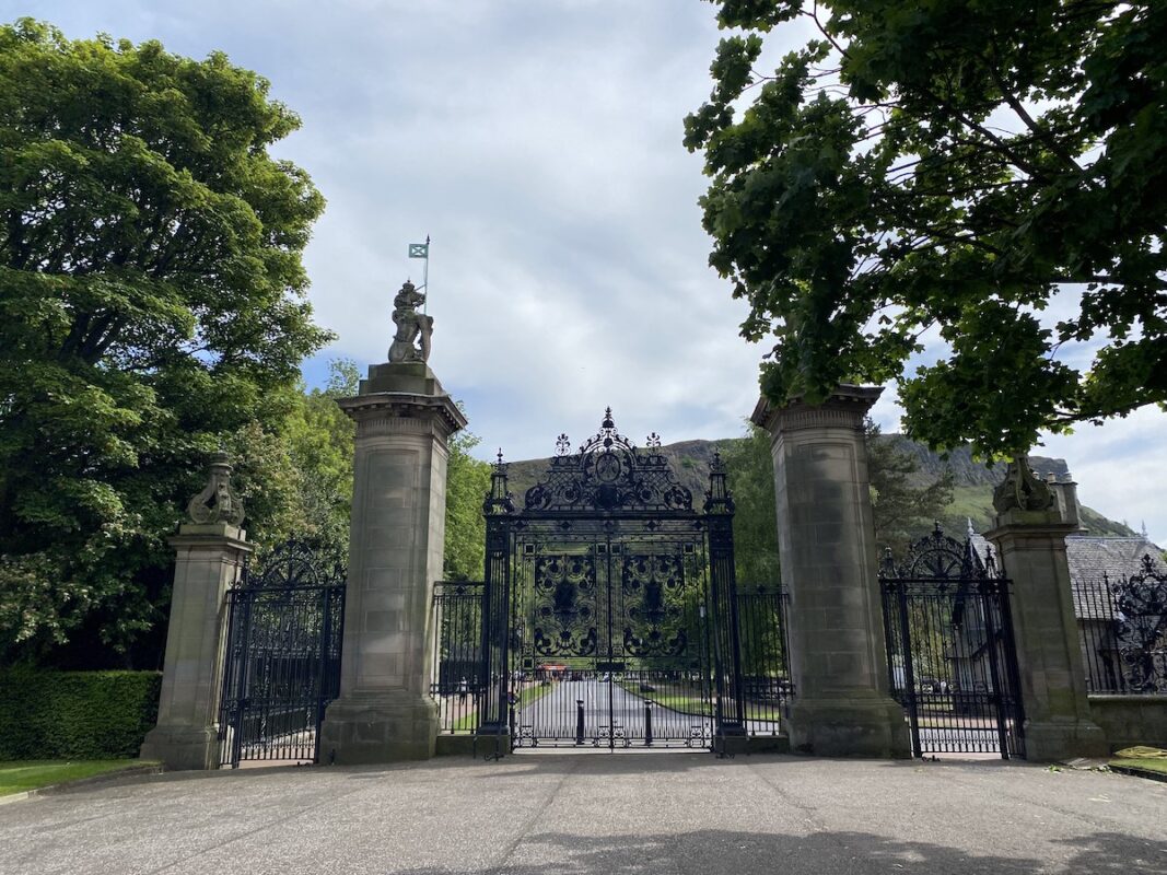 Ornate gates of Holyrood Palace in Edinburgh with intricate ironwork and historic backdrop, ideal for solo travel in Edinburgh.