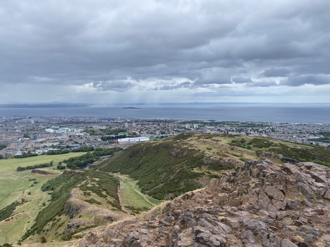 Panoramic view from Arthur's Seat in Edinburgh with city skyline, hills, and coastline, ideal for solo travel in Edinburgh