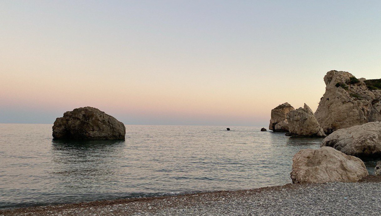 Aphrodite’s Rock Beach at sunset, with golden light reflecting off the sea and the legendary rock formation