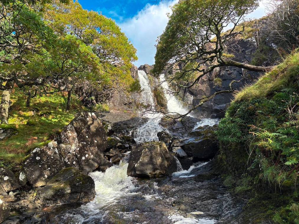 Eos Fors Waterfall on the Isle of Mull, cascading through a lush, forested landscape